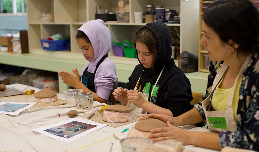 young people working with clay at a table led by an instructor